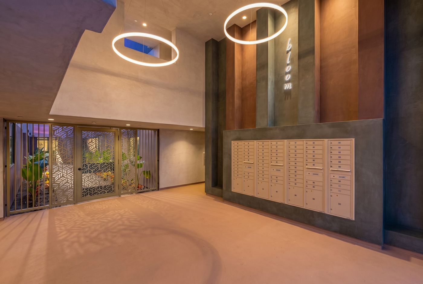 The mailboxes in the lobby in the evening, with the building name on the wall and ring lights overhead.
